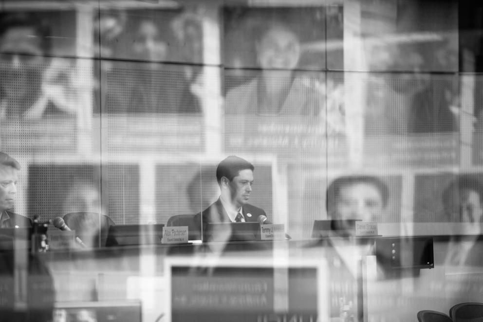 Dan Strauss is seen through reflected images of other councilmembers