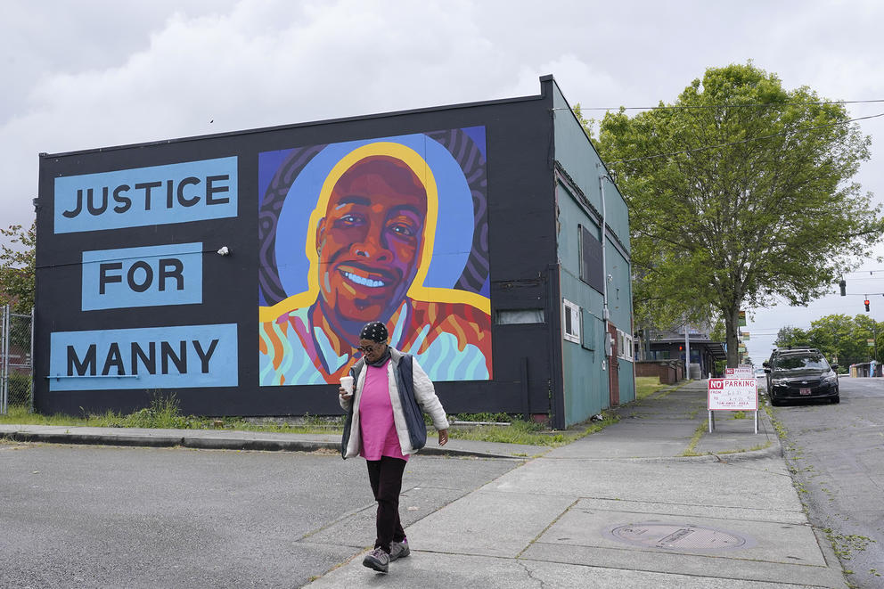 A woman walks past a mural honoring Manuel "Manny" Ellis