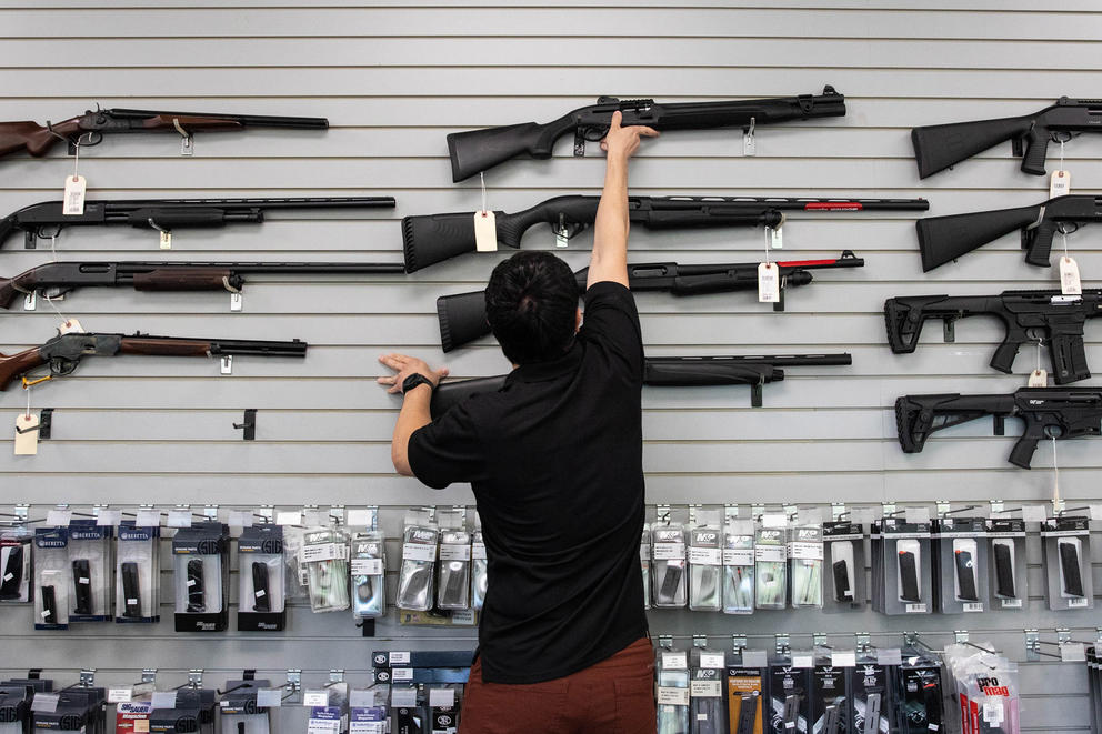 A person mounts a gun in a display area of a store.