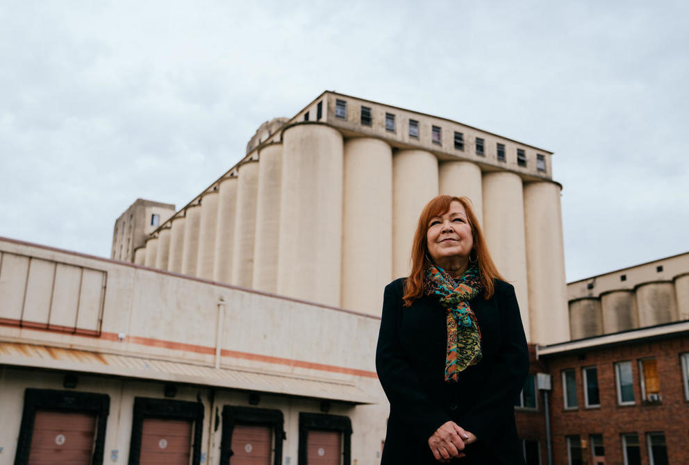 photo of a red headed woman standing in front of flour mill silos