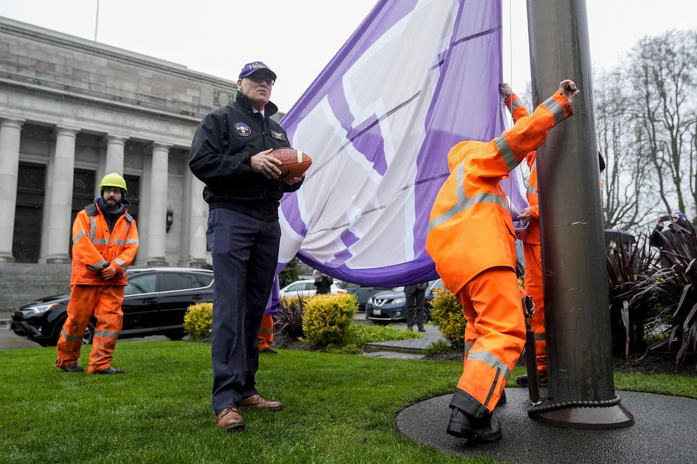 Inslee looks on as workers finish raising the Washington flag on the first day of the legislative session
