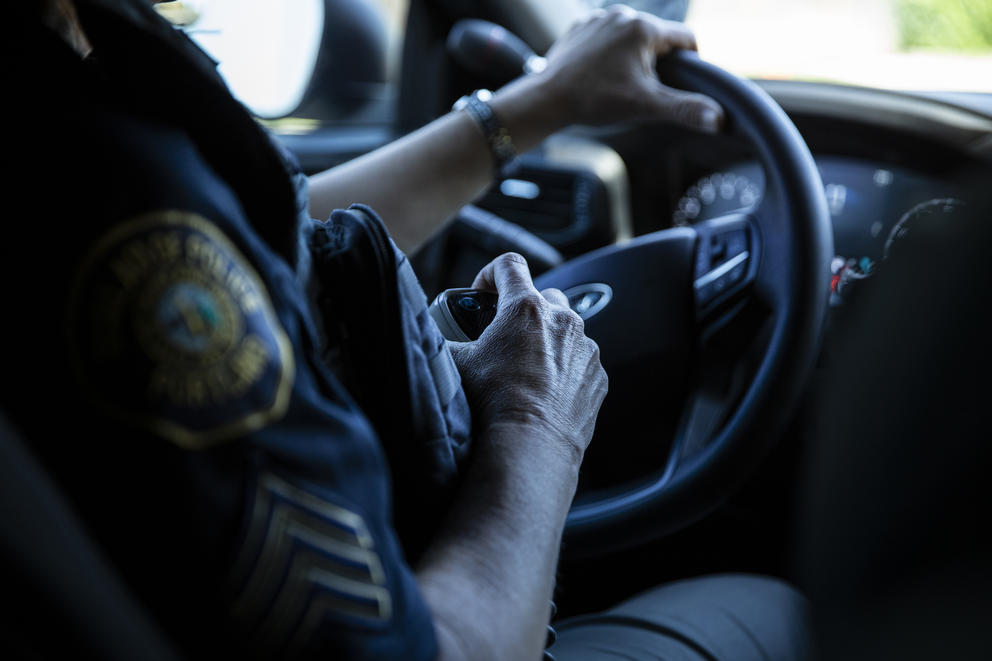 A photo of a steering wheel of a police car while an officer drives it.
