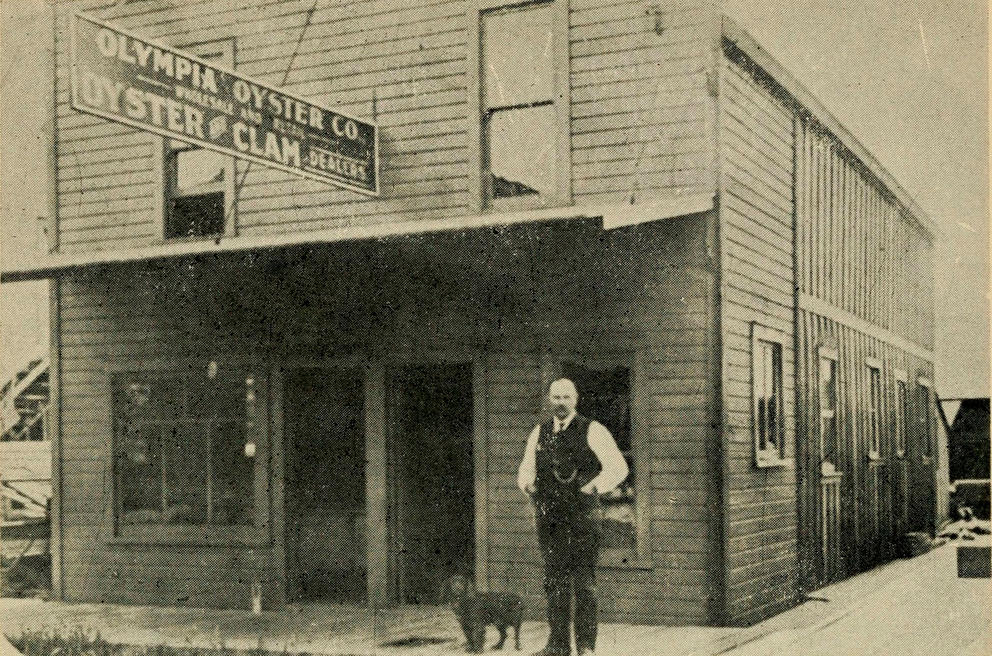 A historic photo from the turn of the 20th century shows a person in front of a building that says Olympia Oyster Company.