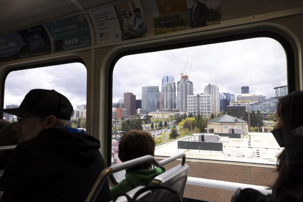 A person looks through a window of a train at a skyline.