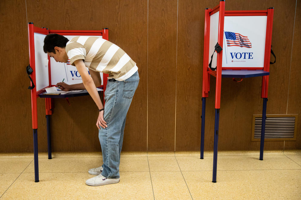 A person votes at a polling place that says "vote"