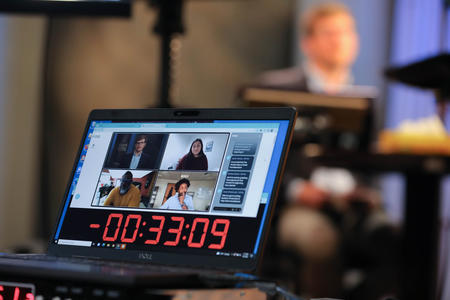 A monitor showing a host and four panelists