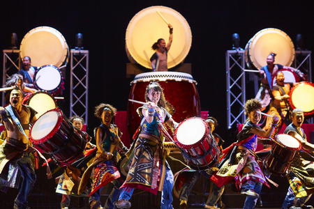 A group of drummers is standing on a stage as they perform