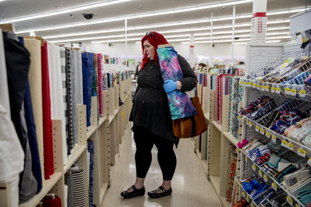 Woman in fabric store holding up roll of colorful fabric