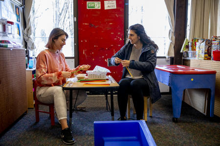 Two childcare workers sit at a table