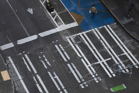 a solitary man walks across a crosswalk