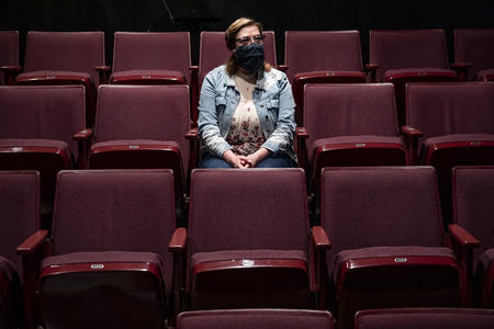Masked person amid theater seats
