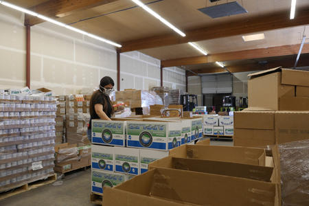 A woman works to organize food in a food bank warehouse