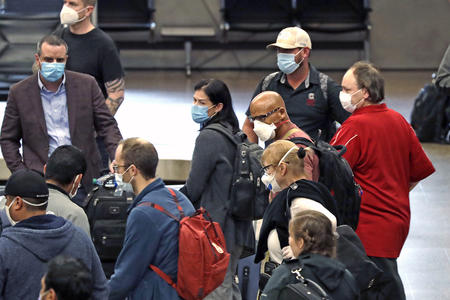 Travelers wear masks as they wait for baggage at Seattle-Tacoma International Airport
