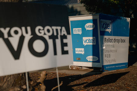 A sign in front of a ballot box reads "You gotta vote"
