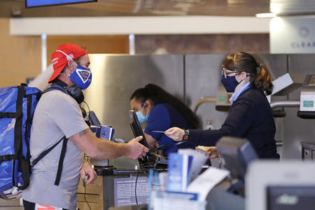 A man with a mask at an airport service counter