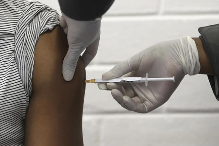 hand holding vaccine administering shot to someone's arm