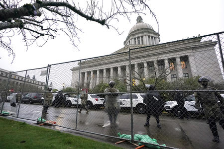 A chain link fence in front of military personnel in front of Capitol dome