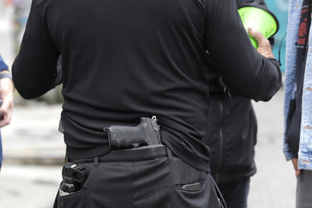 a handgun tucked in the back waste line of a man walking
