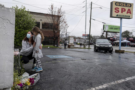 A woman and child visit a memorial at an Atlanta shooting site.