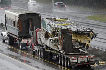 Two damaged train cars sit on flatbed trailers after being taken from the scene of an Amtrak train crash onto Interstate 5 a day earlier Tuesday, Dec. 19, 2017, in DuPont, Wash. Federal investigators say they don't yet know why the Amtrak train was traveling 50 mph over the speed limit when it derailed Monday south of Seattle. (AP Photo/Elaine Thompson)