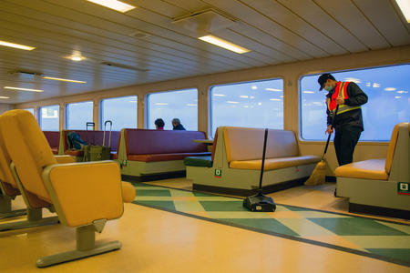 Ferry worker sweeps up on board a ferry
