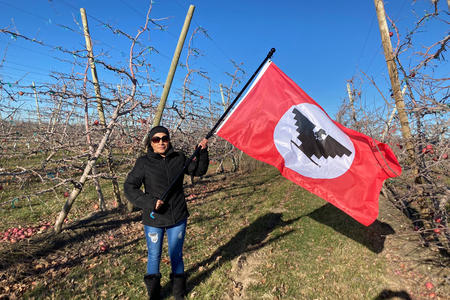 A woman holds a flag in a field