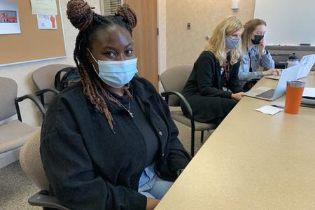 Dayo Onanuga sits in a classroom wearing a face mask