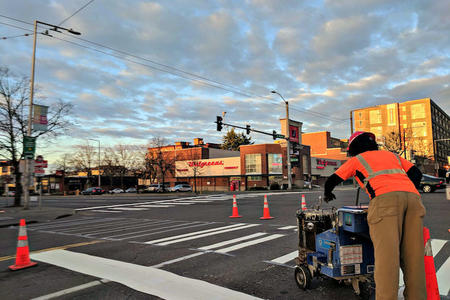 A worker for SDOT repairs a crosswalk in Ballard