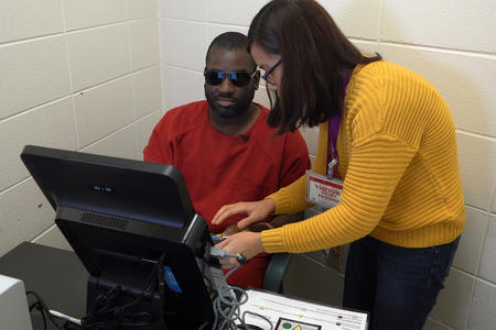 Language Services and Community Engagement Specialist at King County Elections Nhien Huynh assists Jordan Landry, who is visually impaired, as he uses an Accessible Voting Unit to cast a vote 