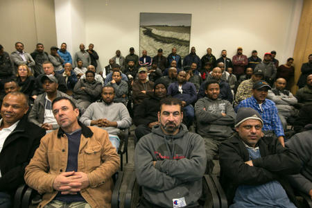 Independent short haul truckers who pick up loads at the Northwest Seaport terminals in Seattle and Tacoma seen in the overflow room at a meeting of Seaport Commissioners at Seattle Tacoma International Airport on Feb. 7, 2018. Credit: Paul Joseph Brown for Investigate West