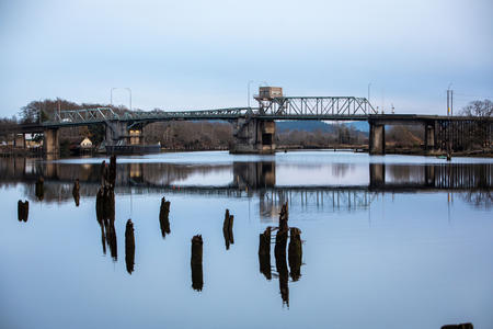 The Simpson Avenue Bridge crosses the Hoquiam River with pilings stick from the water in foreground.