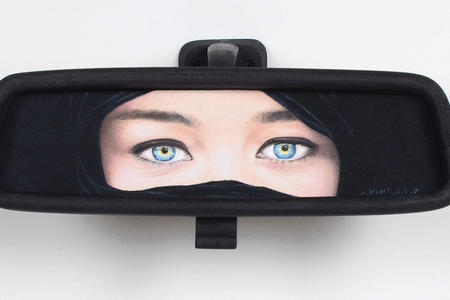 wooden rearview mirror painted with part of the face with eyes and a niqab