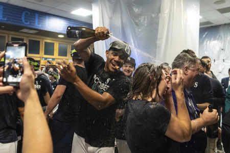 Man spraying champagne on a crowd in a locker room