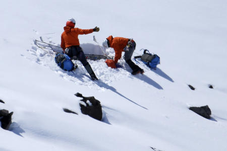 Two men in orange parkas dig in the snow