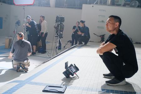 Person squats in empty pool functioning as a film set