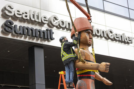 Art Installer Roger Waterhouse of ArtSire uses a crane to install “Mowitch Man,” one of two Salish welcome figures carved by Native American artist Andrea M. Wilbur-Sigo at the new Seattle Convention Center Summit building.