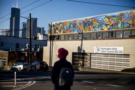 A person passes by a building with a mural