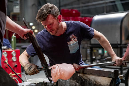 A man works with blown glass