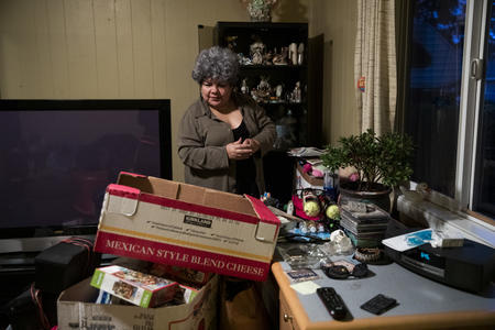 Irma Serrano packs thing into a box in her living room