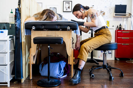 Avery Osajima gives Lauren Clinkenbeard a stick and poke tattoo at Lilith Tattoo shop in Fremont on Aug. 21, 2019. (Photo by Dorothy Edwards/Crosscut)