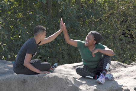 Jas Maisonet and Alison Mariella Désir high five atop a boulder in Magnuson Park