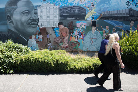 Women walk by a mural in Tacoma's Hilltop neighborhood. 