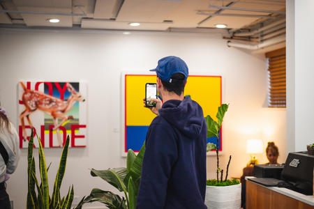 Person stands ina space with two colorful paintings in the back
