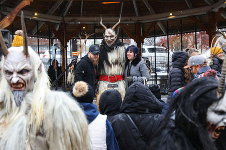 Three people dressed as Krampus take photos with visitors in downtown Leavenworth