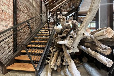 photo of a staircase next to which is a huge stack of giant driftwood