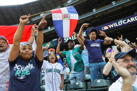 a group of fans in Mariner's jerseys cheer in a stadium