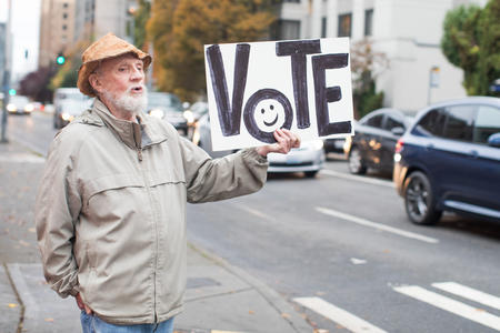 David Nash holding a sign that says "Vote" on the corner of First Hill in Seattle