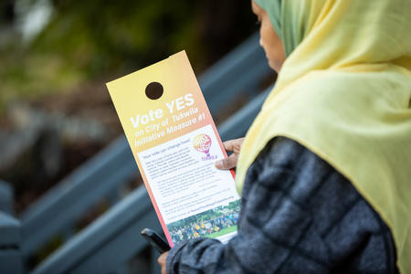 Tukwila resident looks at a flier touting a proposed minimum wage increase on the election ballot. 