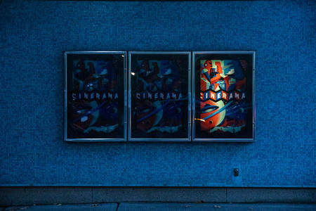 three posters hang horizontally, only the right one is lit up and says “Cinerama”