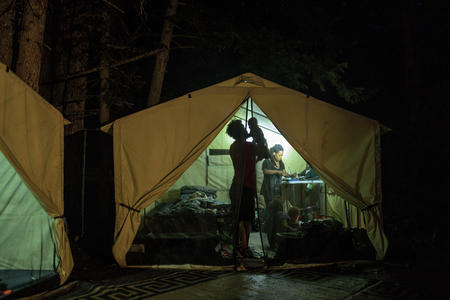 A man holds a baby aloft inside a canvas tent